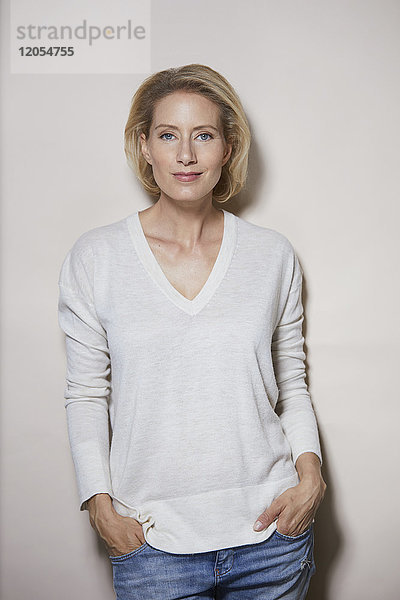 Porträt einer lächelnden blonden Frau vor hellem Hintergrund