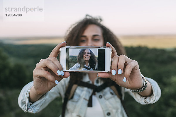 Lächelndes Teenagermädchen nimmt Selfie in der Natur auf