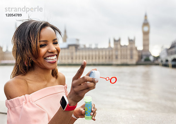 UK  London  glückliche Frau macht Seifenblasen in der Nähe von Palace of Westminster