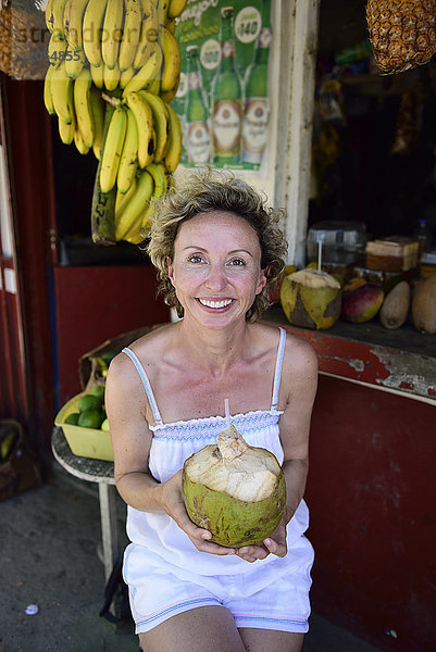 Porträt einer lächelnden Frau mit Kokosnuss im Tropenfruchtshop