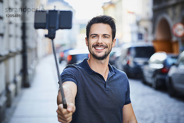 Mann fotografiert mit Smartphone auf Selfie-Stick montiert