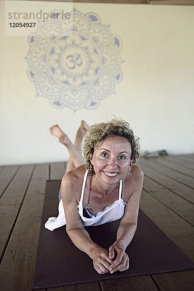 Porträt einer lächelnden Frau auf Yogamatte liegend