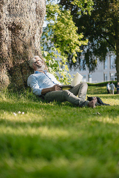 Erwachsener Mann mit Laptop entspannt im Park