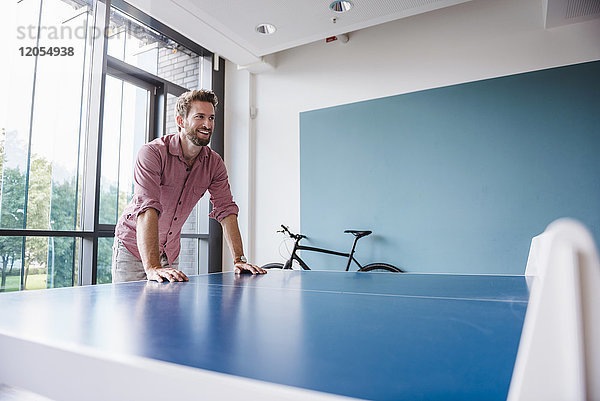 Mann im Pausenraum des modernen Büros am Tischtennistisch