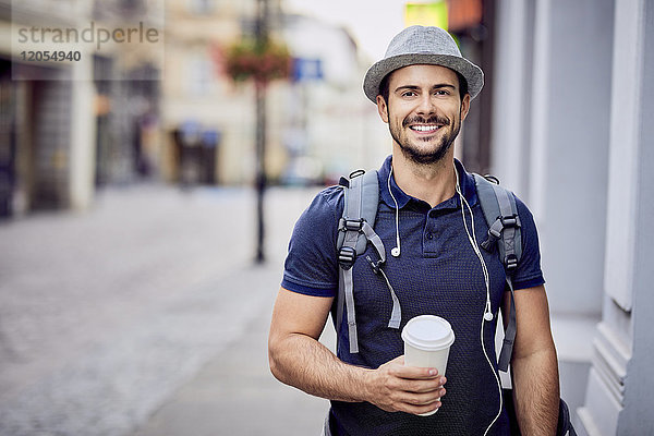 Portrait eines Reisenden mit Rucksack  der Kaffee hält