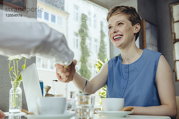 Geschäftsmann und Geschäftsfrau beim Händeschütteln im Cafe