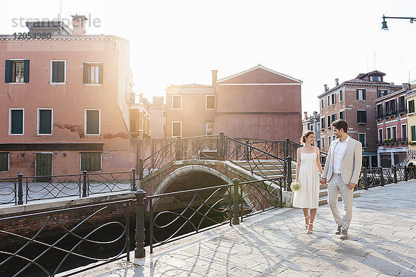 Italien  Venedig  Brautpaar geht bei Sonnenaufgang Hand in Hand
