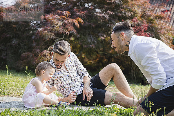 Schwules Paar  das mit seinem Kind im Garten spielt.