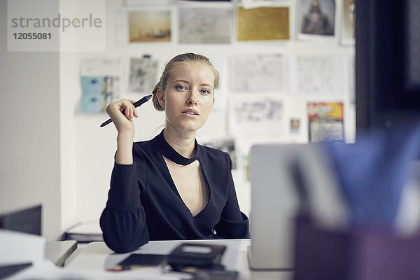 Porträt einer jungen Geschäftsfrau am Schreibtisch im Büro