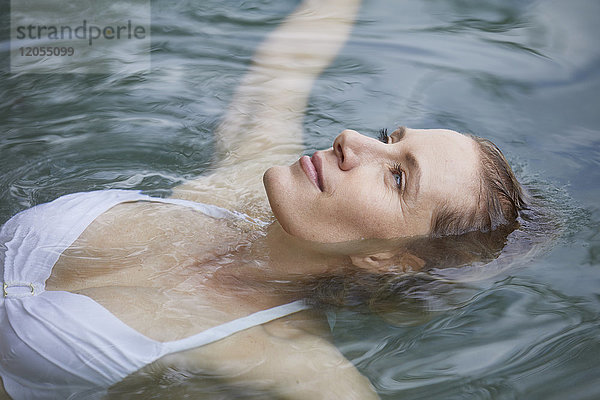 Porträt einer entspannten Frau  die auf dem Wasser schwebt