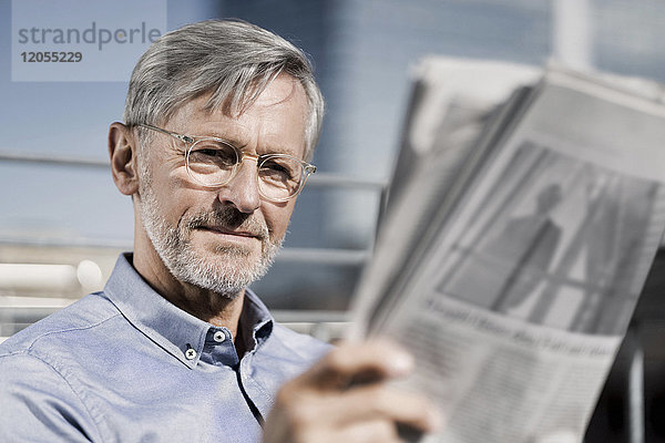 Grauhaariger Mann beim Zeitungslesen
