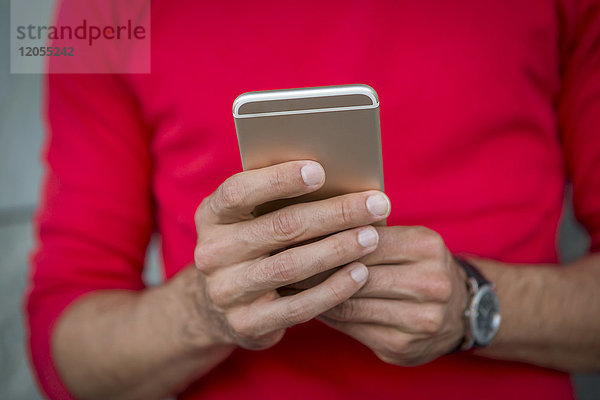 Hände des Mannes beim Schreiben von Textnachrichten auf einem Smartphone