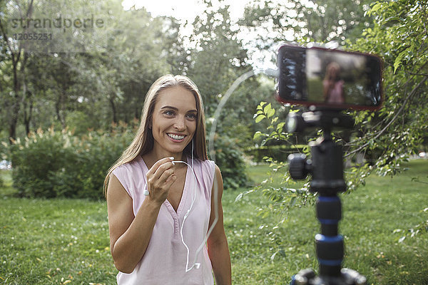 Lächelnde junge Frau beim Fotografieren auf einer Wiese