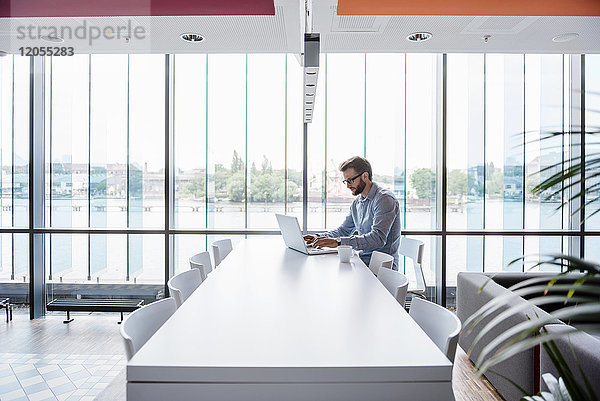Mann mit Laptop am Konferenztisch im Büro sitzend