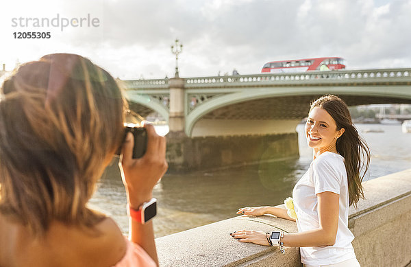 UK  London  Frau beim Fotografieren ihres Freundes in der Nähe der Westminster Bridge