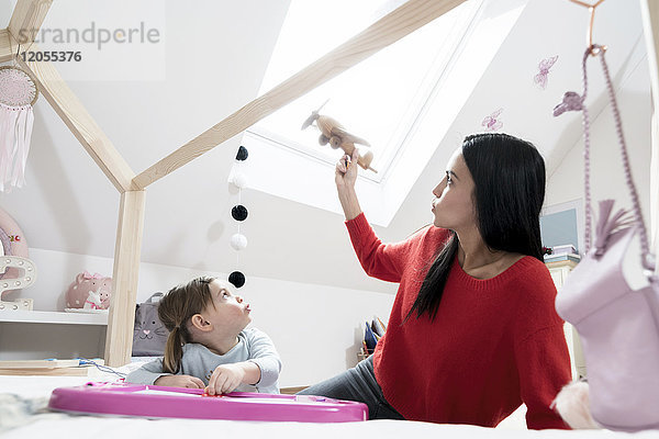 Mutter und Tochter spielen mit dem Spielzeugflugzeug im Kinderzimmer