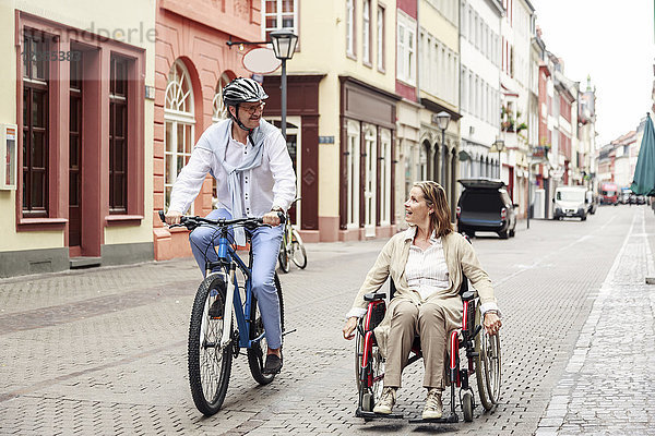 Deutschland  Heidelberg  Frau im Rollstuhl und Mann auf dem Fahrrad in der Stadt