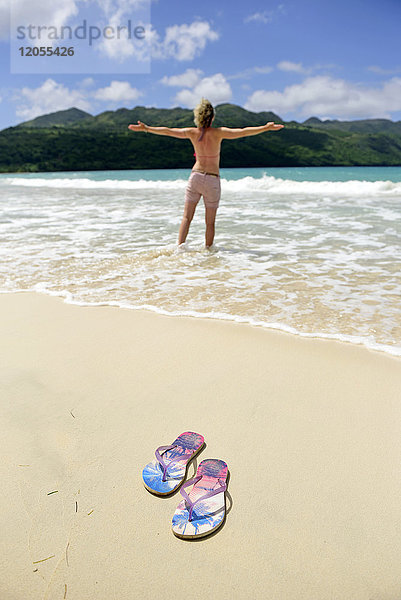 Dominikanische Republik  Samana  Flip-Flops am Strand und Frau im Meer