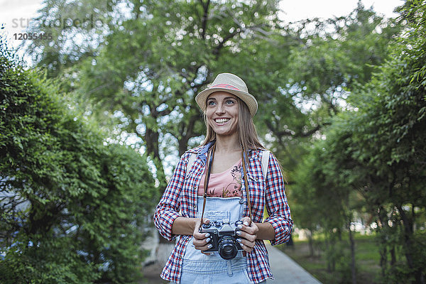 Lächelnde junge Frau mit Kamera im Park