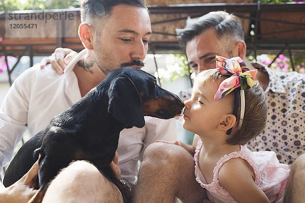 Schwules Paar mit Tochter und Hund auf dem Balkon