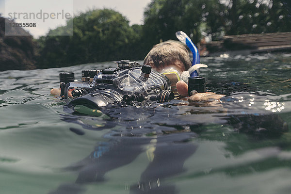 Mann mit Unterwasser-DSLR-Kameragehäuse im See