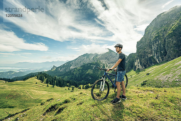 Deutschland  Bayern  Pfronten  junger Mann mit Mountainbike auf der Alm bei Aggenstein