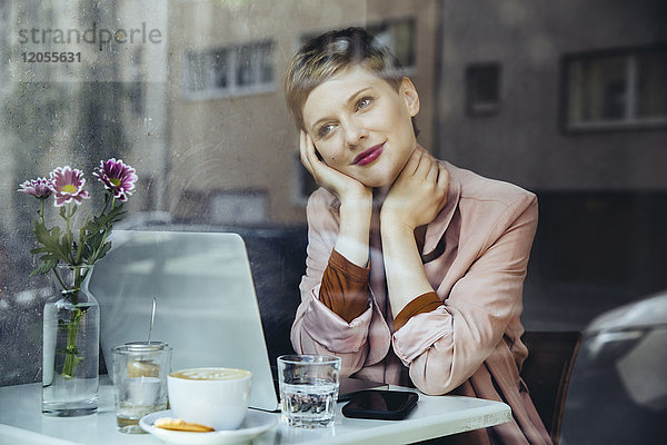 Frau mit ihrem Laptop genießt die Aussicht in einem Cafe