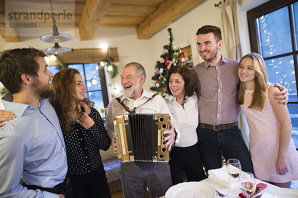 Senior Mann spielt Akkordeon für glückliche Familie an Weihnachten