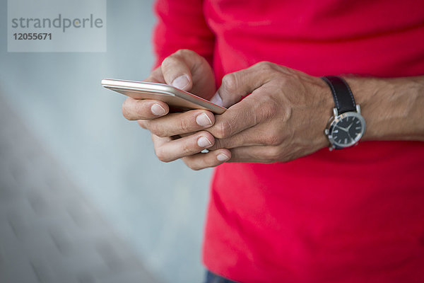 Hände des Mannes beim Schreiben von Textnachrichten auf einem Smartphone