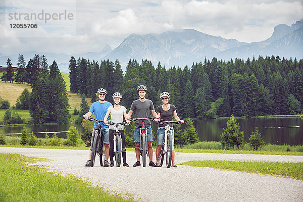Deutschland  Bayern  Pfronten  Porträt der glücklichen Familie mit Mountainbikes am Ladeside