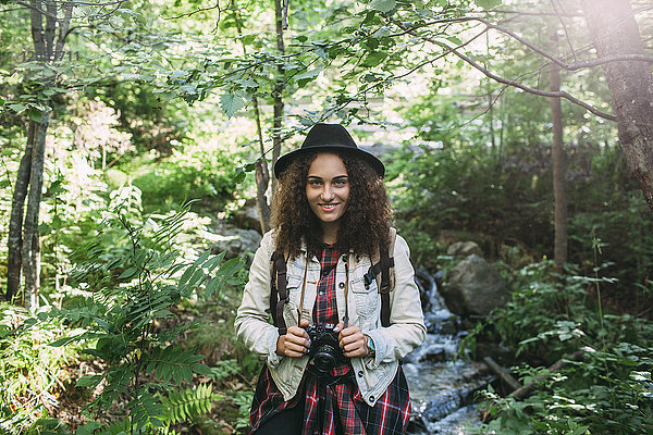 Porträt eines lächelnden Teenagermädchens mit Kamera in der Natur