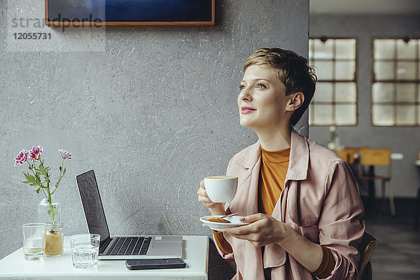 Frau mit ihrem Laptop bei einer Tasse Kaffee im Cafe