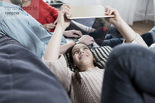 Mädchen mit Familie auf Sofa liegend mit Tablette