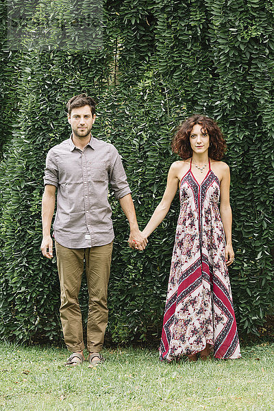Porträt eines Paares  das Hand in Hand in einem Park steht.