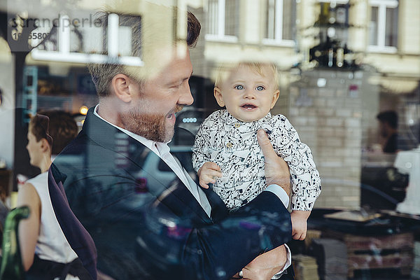 Geschäftsmann hält seinen kleinen Jungen im Café.