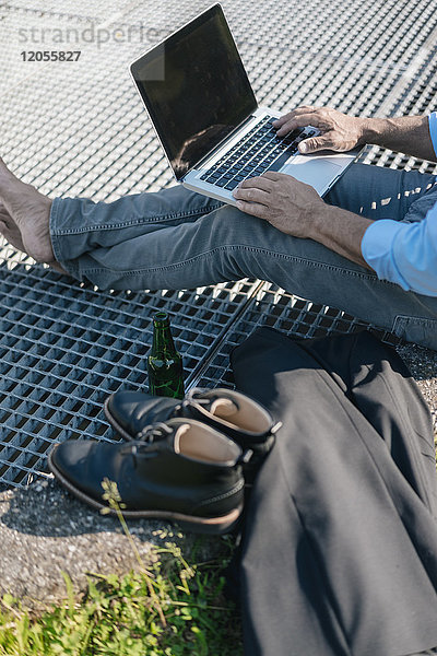 Mann mit Bier und Laptop im Freien