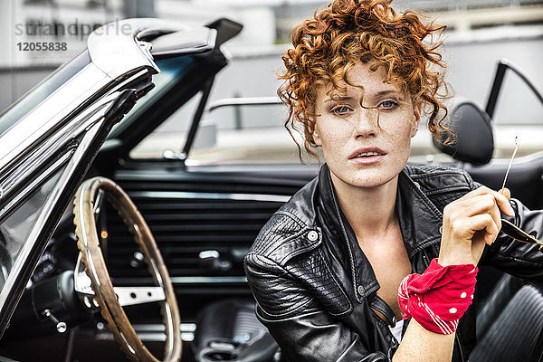Porträt einer selbstbewussten rothaarigen Frau im Sportwagen
