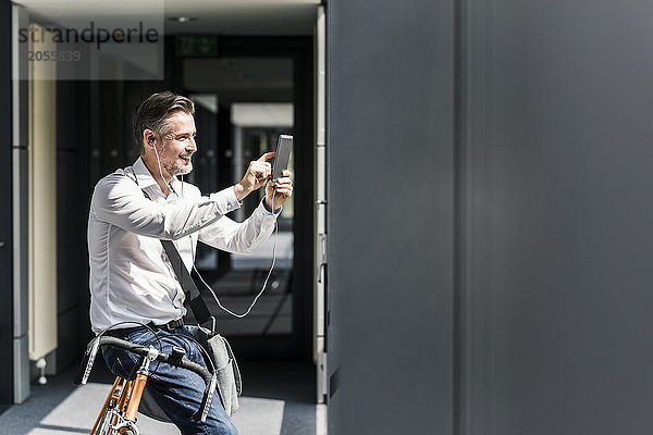 Geschäftsmann mit Fahrrad im Bürogang per Handy