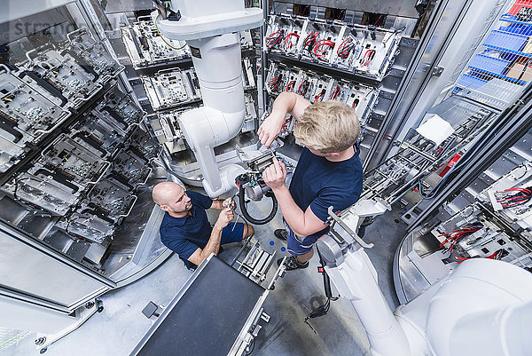 Zwei Kollegen bei einem Industrieroboter in einer modernen Fabrik