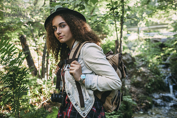 Porträt eines jungen Mädchens mit Rucksack und Kamera in der Natur