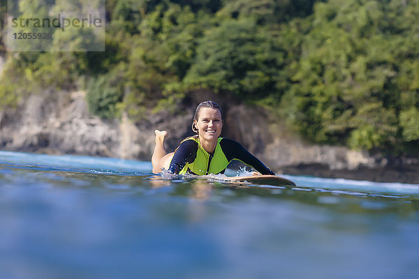 Indonesien  Bali  lächelnde Frau auf dem Surfbrett liegend