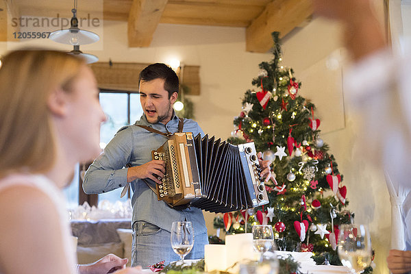 Junger Mann spielt Akkordeon am Weihnachtstisch