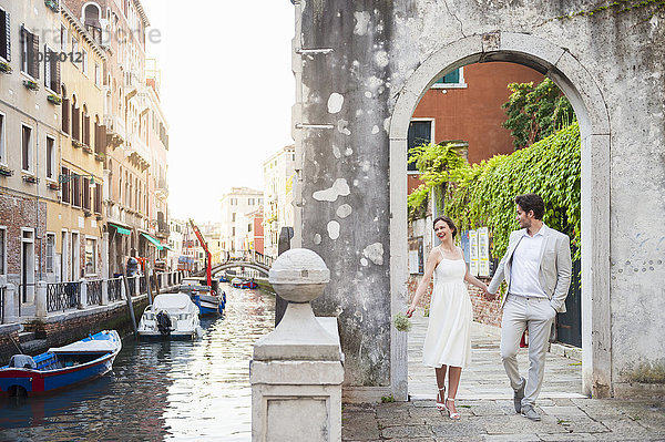 Italien  Venedig  Brautpaar geht Hand in Hand durch den Torbogen