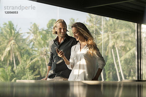 Lächelndes Paar mit Smartphone im Designhaus