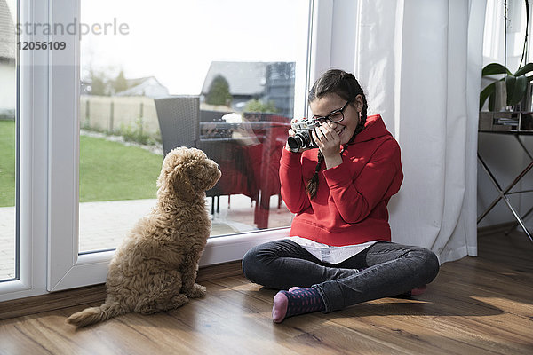 Mädchen beim Fotografieren ihres Hundes im Wohnzimmer
