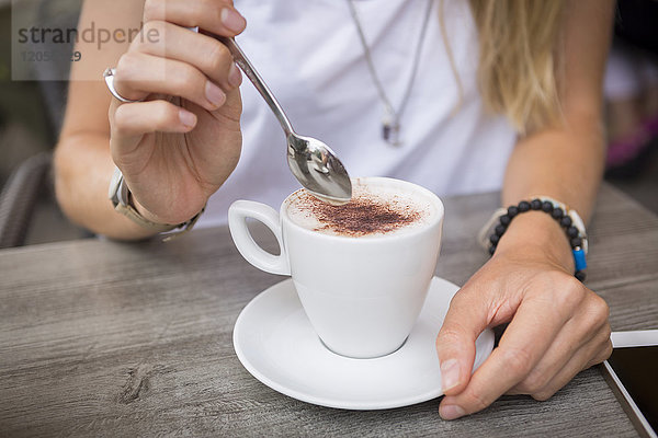 Nahaufnahme einer Frau mit Cappuccino in einem Straßencafé