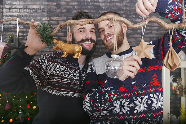 Schwules Paar schmückt einen Zweig zur Weihnachtszeit