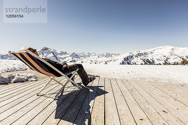 Österreich  Damuels  Senior im Liegestuhl auf dem Sonnendeck in der Winterlandschaft