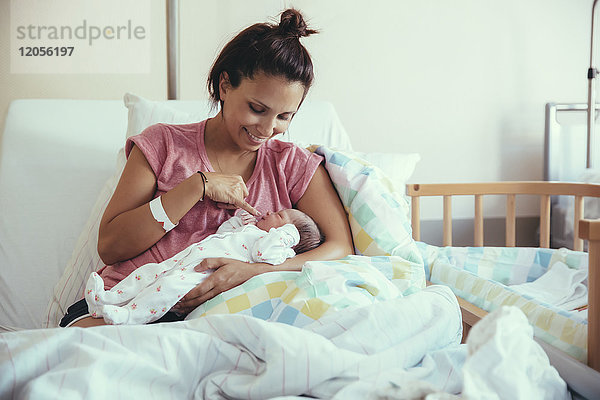 Glückliche Mutter mit ihrem Neugeborenen im Krankenhausbett