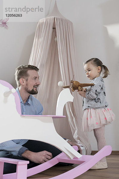 Vater spielt mit Kleinkind-Tochter in ihrem Kinderzimmer